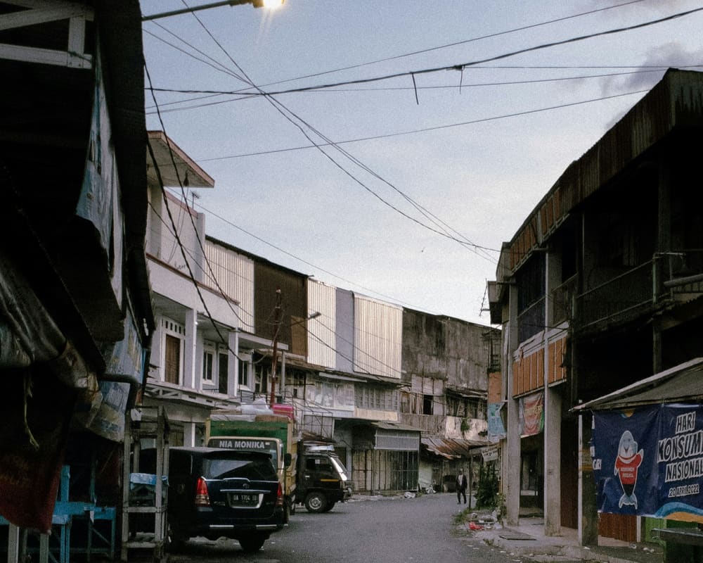 Jalan di Banjarmasin dengan deretan ruko dan kendaraan terparkir.